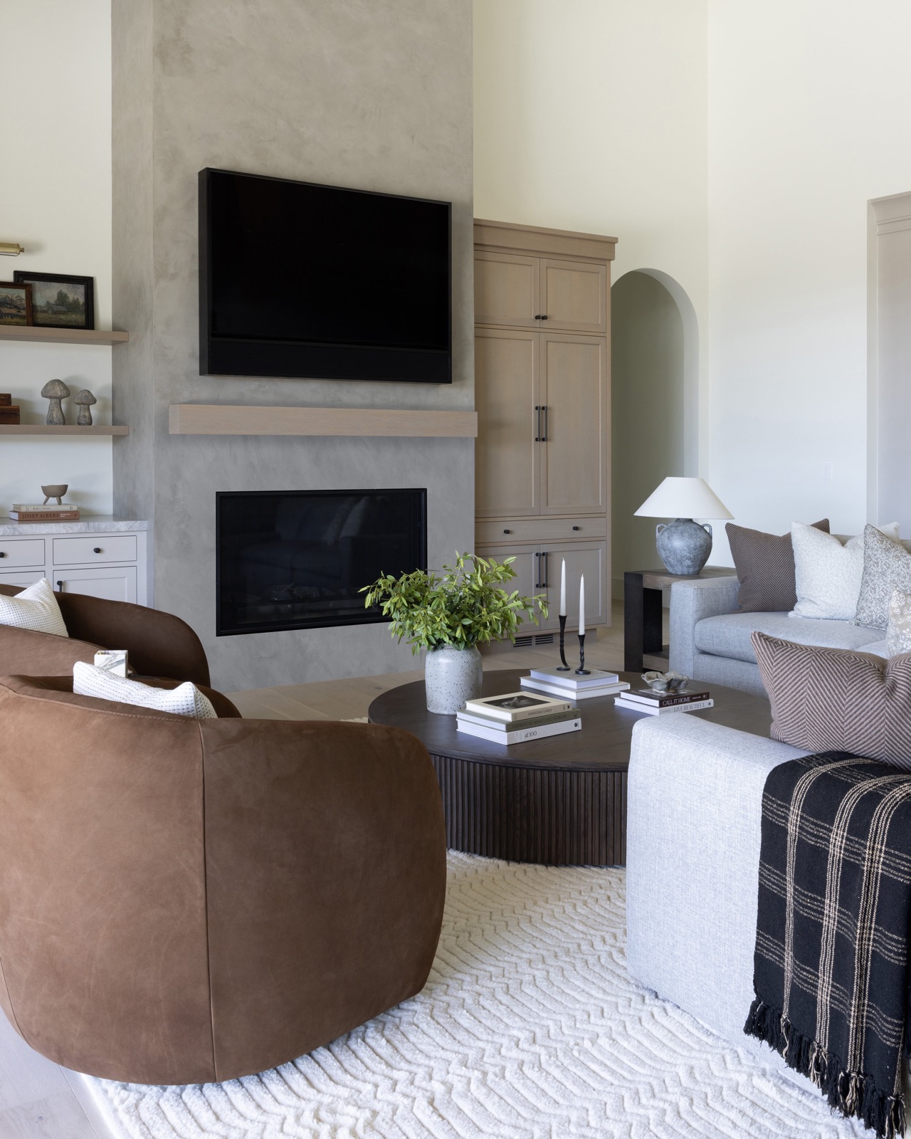 Living room with a concrete fireplace and curved leather chair.