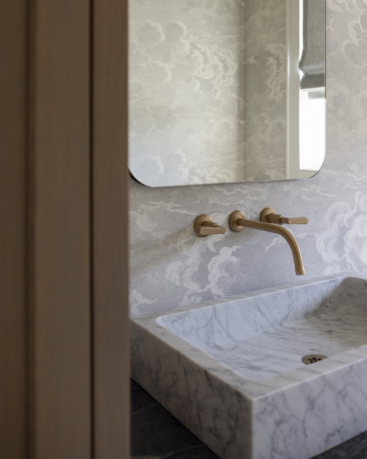 Powder bath, marble trough sink and brass wall-mount faucet.