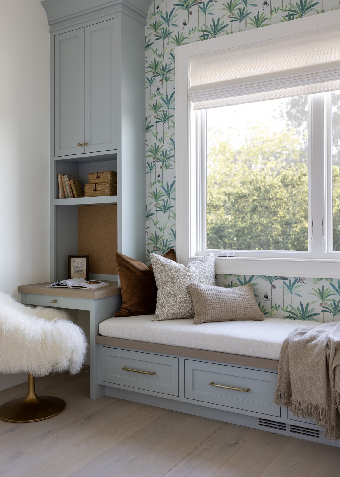A window-seat reading nook and built-in desk, wrapped in palm-print wallpaper.