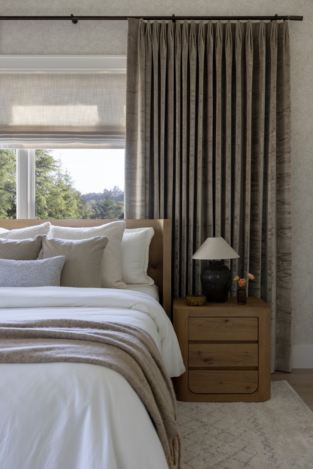 Bedroom with an oak bed, velvet drapery, and a window to the pines.